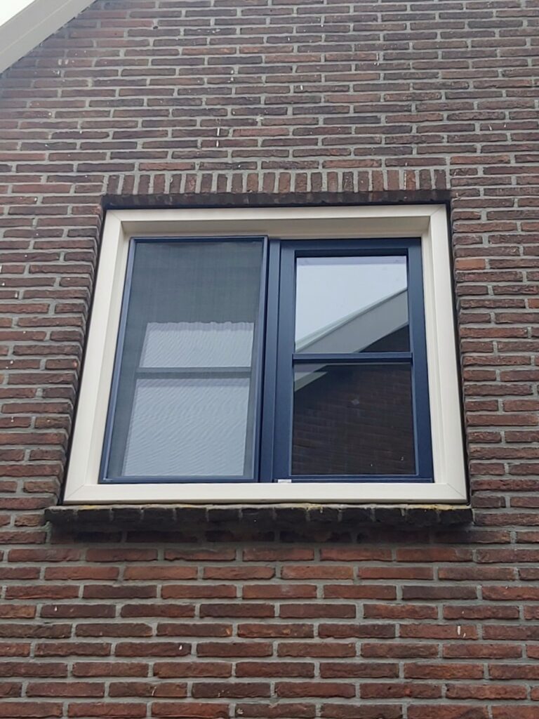 Wit kozijn met blauwe draai-kiepramen en inzethor.
