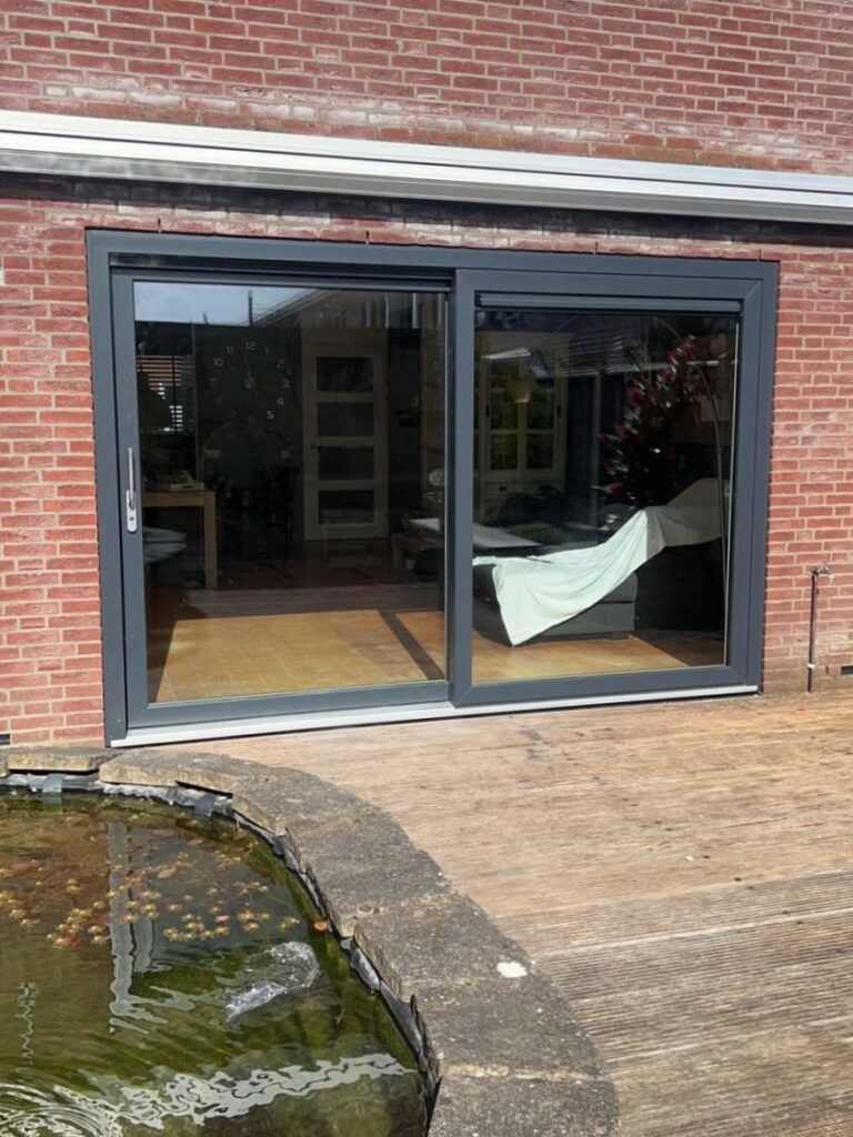 Kunststof hefschuifpui in antraciet met ventilatierooster in het vaste raam (rechts)